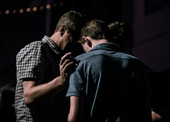 People praying together in dimly lit room.