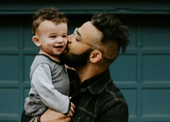 Man kissing smiling baby on cheek.